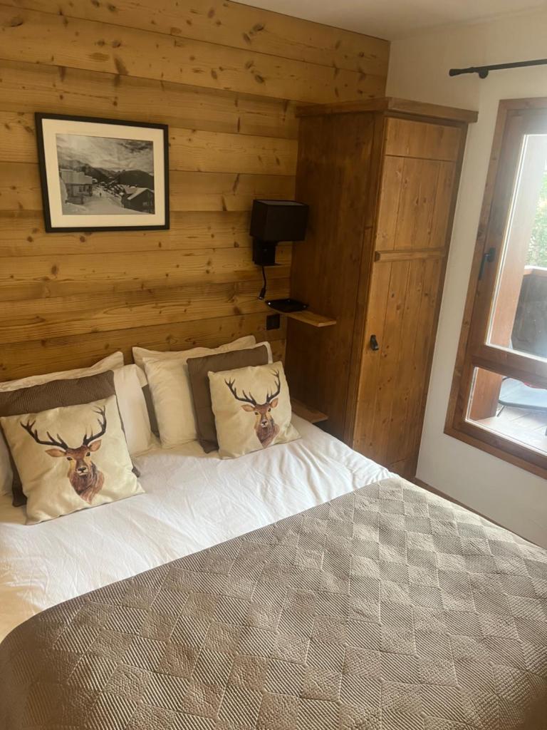 - une chambre avec un lit et un mur en bois dans l'établissement Arc 1950 Ski in Ski out and Spa- Newly refurbished 153 Sources De Marie- 2 bedroom , 2 bathroom-Sleeps 4-6, Mont Blanc view from every window, Free WiFi, à Arc 1950 33 autres photos
