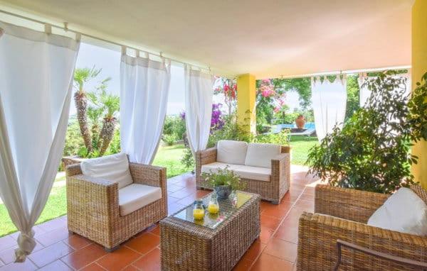 d'une terrasse avec des chaises en osier et une table basse. dans l'établissement GreenVilla, à La Caletta