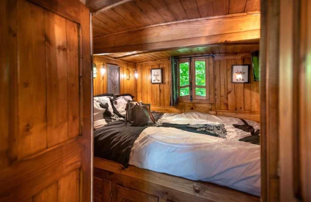 une chambre avec un lit dans une cabane en bois dans l'établissement Camping 3 étoiles - Piscine - ccbaeei, à Grand-Laviers