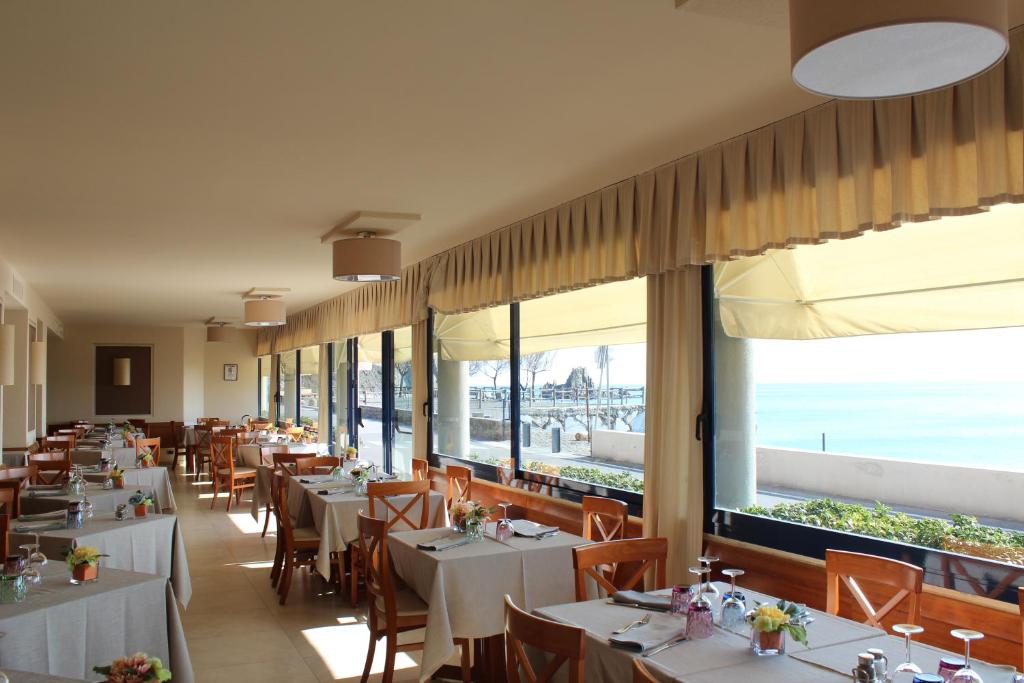 un restaurant avec tables et chaises avec vue sur l'océan dans l'établissement Hotel 4 Venti spa & wellness, à Sestri Levante