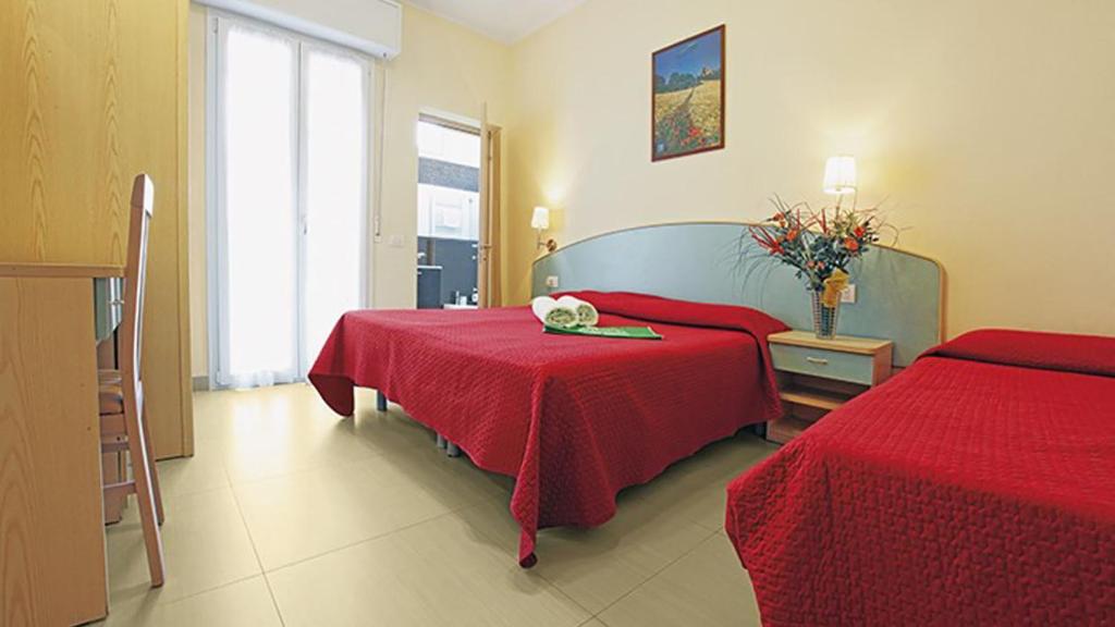 une chambre d'hôtel avec deux lits avec des draps rouges dans l'établissement HOTEL CUBA nuova gestione, à Rimini