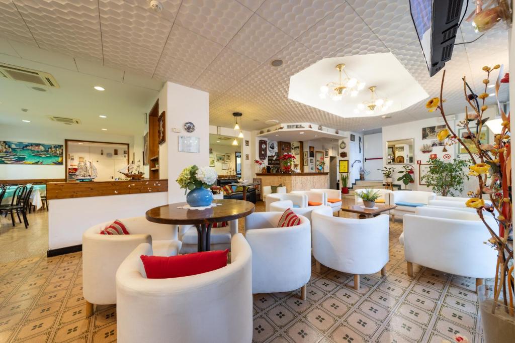 - une salle d'attente avec des chaises blanches et une table dans l'établissement Hotel Cortina, à Rimini
