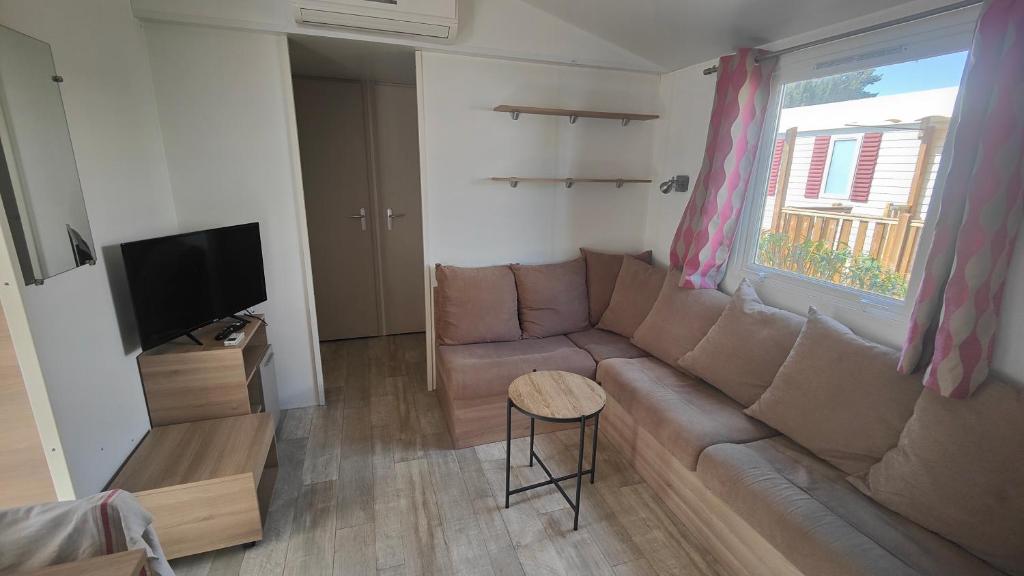 un salon avec un canapé et une télévision dans l'établissement Mobile-Home 6-8 personnes - camping " Les sables du midi", à Valras-Plage