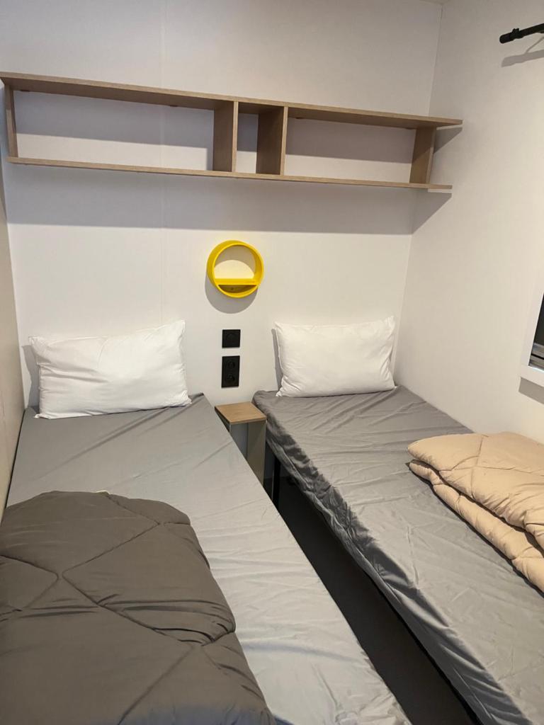 - 2 lits dans une petite chambre avec un miroir jaune dans l'établissement Mobil home tout confort côte bleue, à Carry-le-Rouet