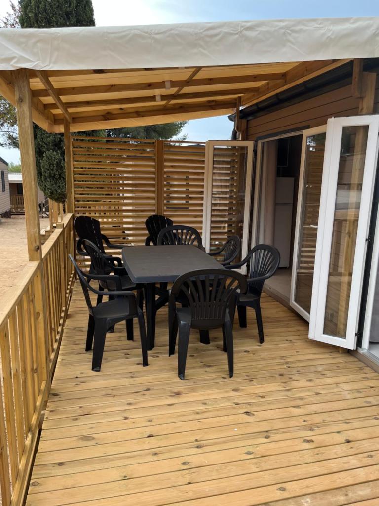 un patio avec une table et des chaises sur une terrasse dans l'établissement Mobil home tout confort côte bleue, à Carry-le-Rouet
