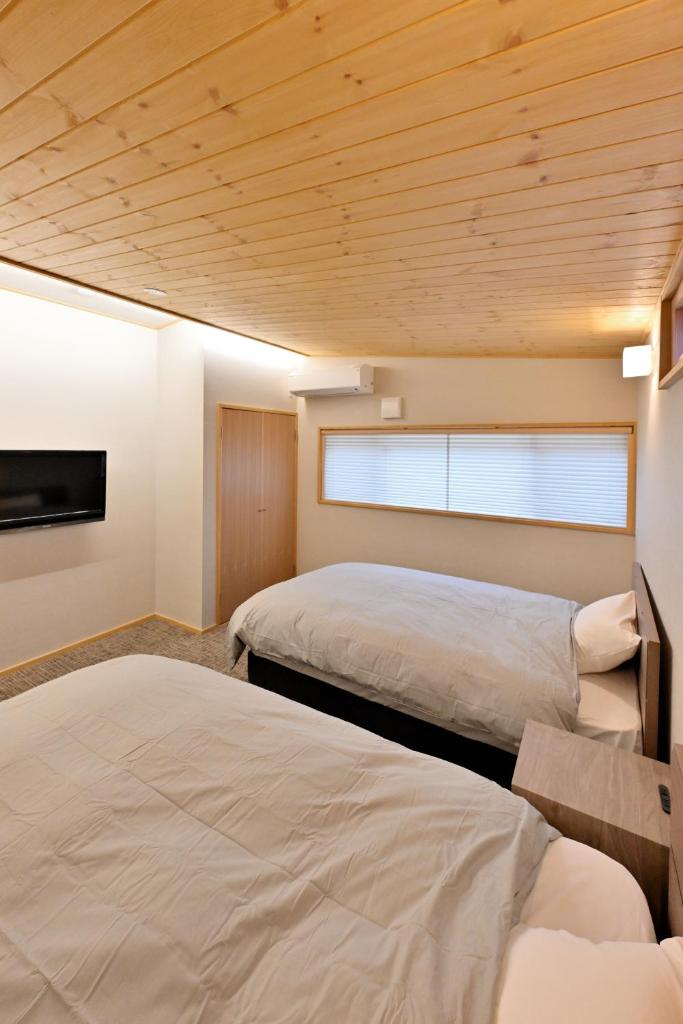 deux lits dans une chambre avec plafonds en bois dans l'établissement Shikinosato Hanamura, à Minamioguni