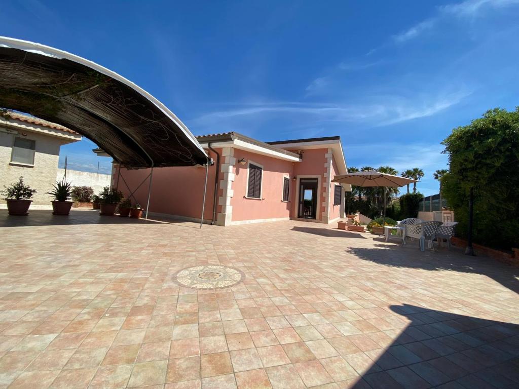 une maison avec une allée en briques et une terrasse dans l'établissement Villa Amos Marzamemi San Lorenzo, à Reitani