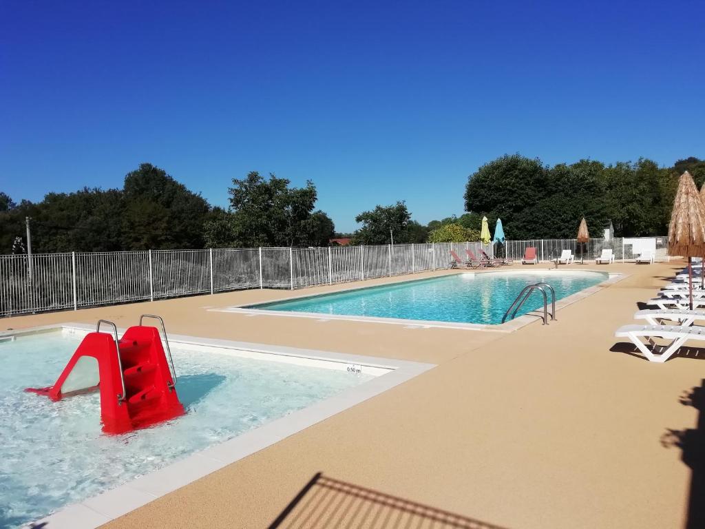 une piscine avec un toboggan rouge au milieu dans l'établissement LES PIERRES CHAUDES, à Veyrignac