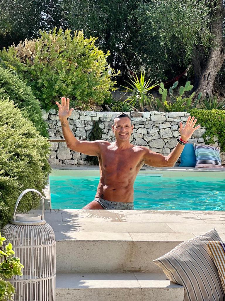 Un homme debout dans une piscine avec les mains levées dans l'établissement Villa del 1700 immersa nel verde, Poggio al Sole Vieste, à Vieste
