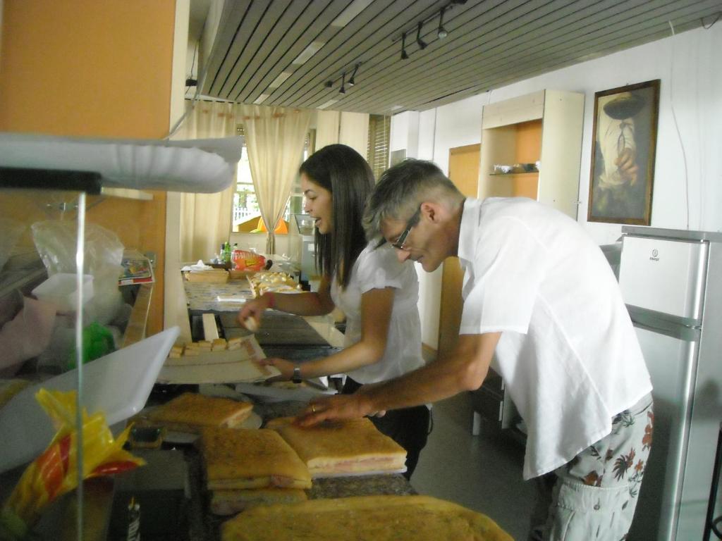 Un homme et une femme préparant de la nourriture dans une cuisine dans l'établissement Hotel Residenza Giardino, à Bellaria-Igea Marina 163 autres photos