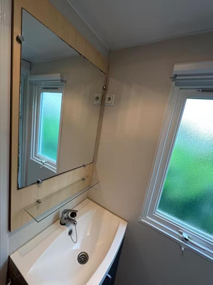 une salle de bain avec un lavabo avec un miroir et une fenêtre dans l'établissement Mobil-home 5 personnes, à Ouistreham 6 autres photos