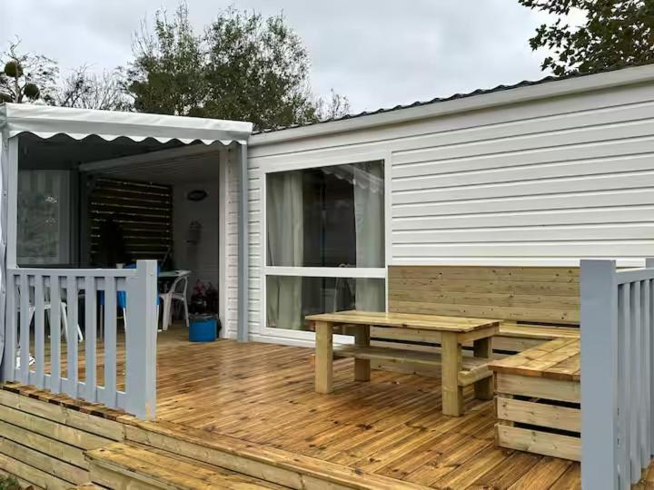 une terrasse en bois avec un banc et une table dans l'établissement Mobil-home 5 personnes, à Ouistreham