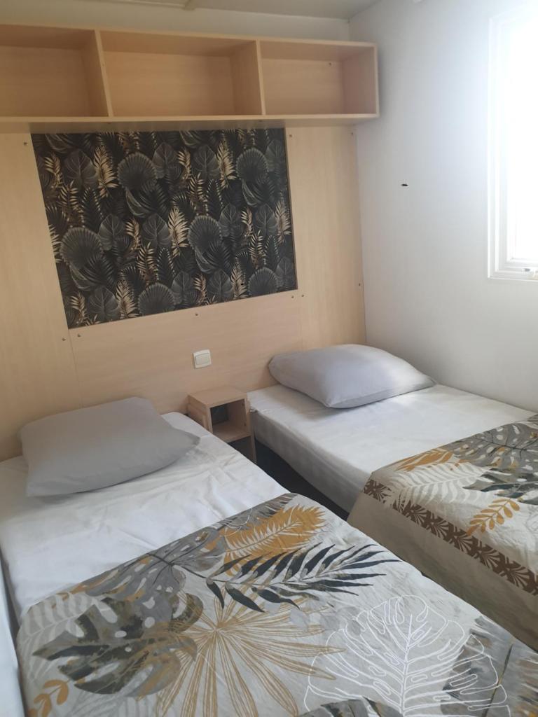 une chambre avec deux lits et un tableau au mur dans l'établissement Mobil home 4 personnes avec clim, à La Roque-dʼAnthéron 8 autres photos