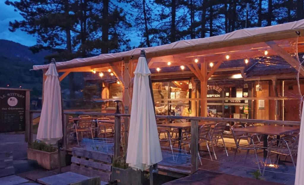 un restaurant avec des parasols blancs, des tables et des chaises dans l'établissement Cabane en bois POD 1, à Champfromier