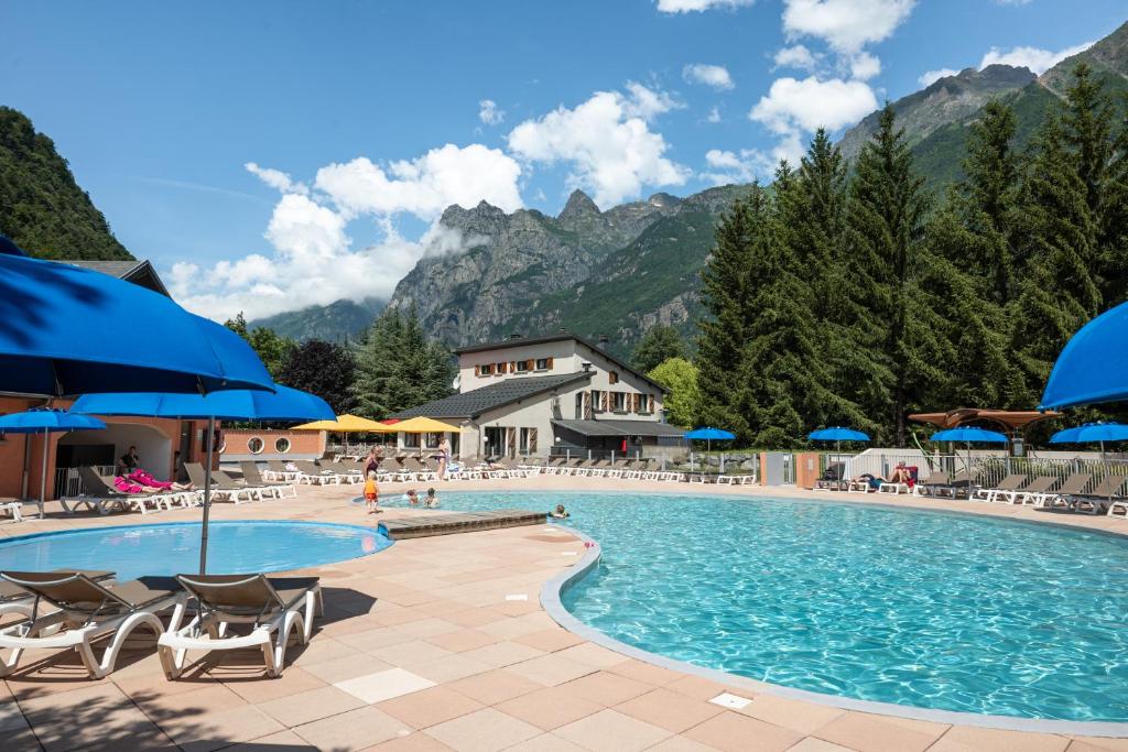 une grande piscine avec chaises et parasols dans l'établissement Camping RCN Belledonne, au Bourg-dʼOisans
