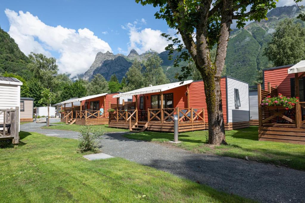 Une rangée de cottages avec des montagnes en arrière-plan dans l'établissement Camping RCN Belledonne, au Bourg-dʼOisans
