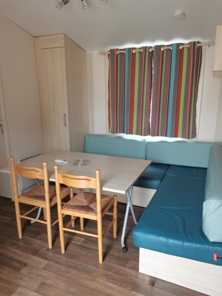 un salon avec une table et un canapé bleu dans l'établissement Gaby mobil Home, à Port-la-Nouvelle