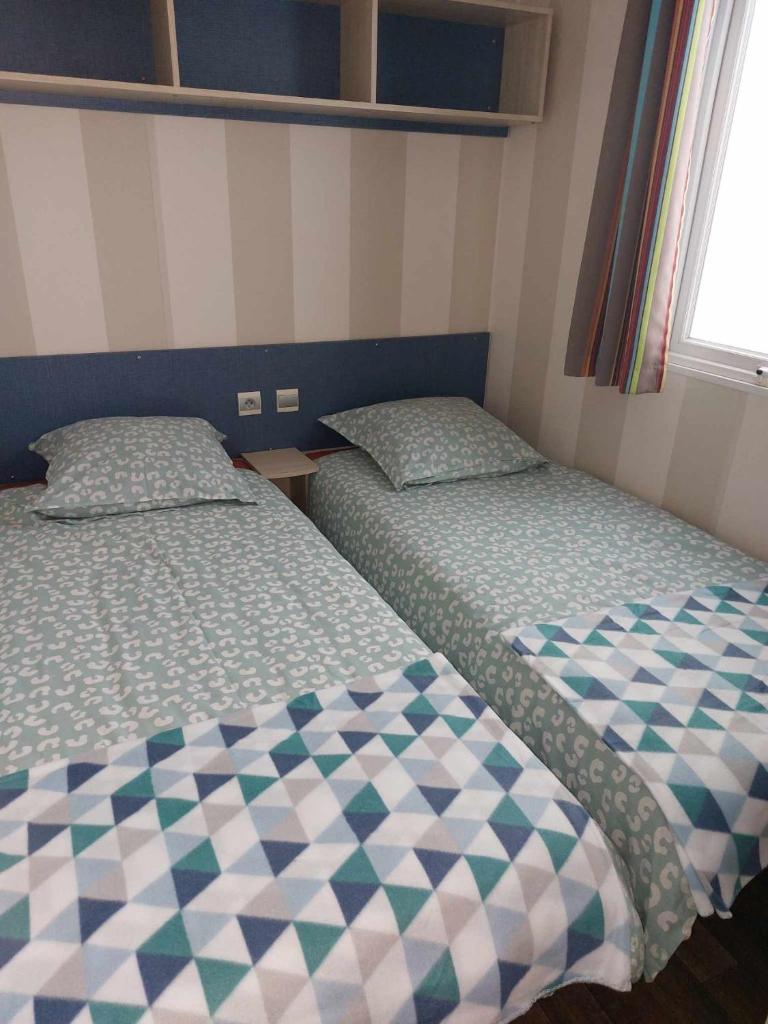 deux lits dans une petite pièce avec dans l'établissement Gaby mobil Home, à Port-la-Nouvelle