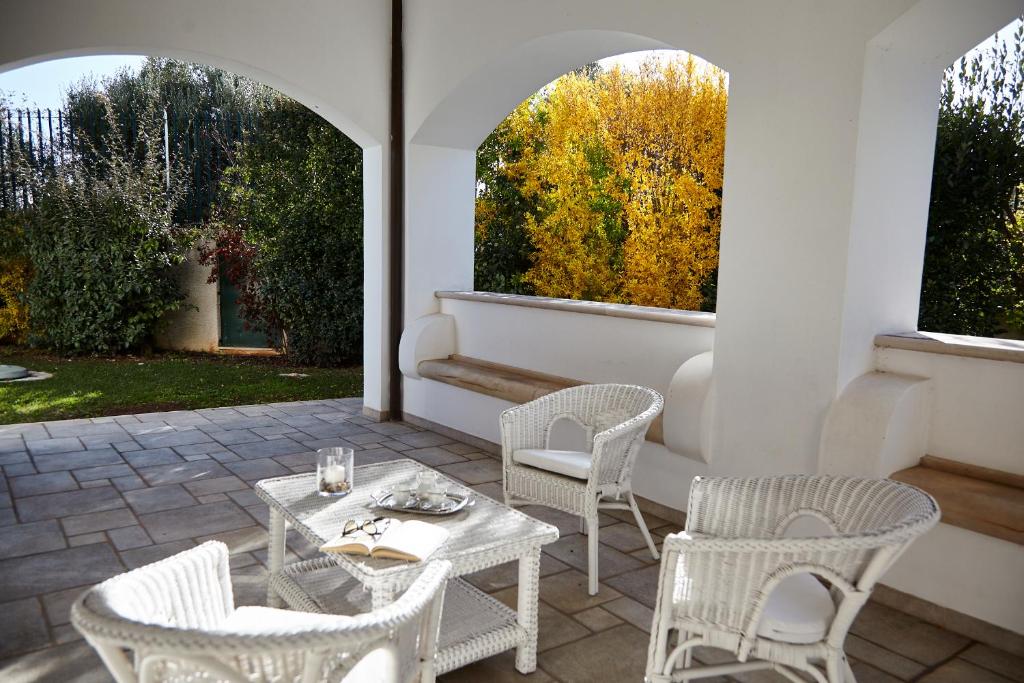d'une terrasse avec des chaises blanches, une table et deux fenêtres. dans l'établissement Villa Carrubo Peroscia by STHEY, à Padresergio