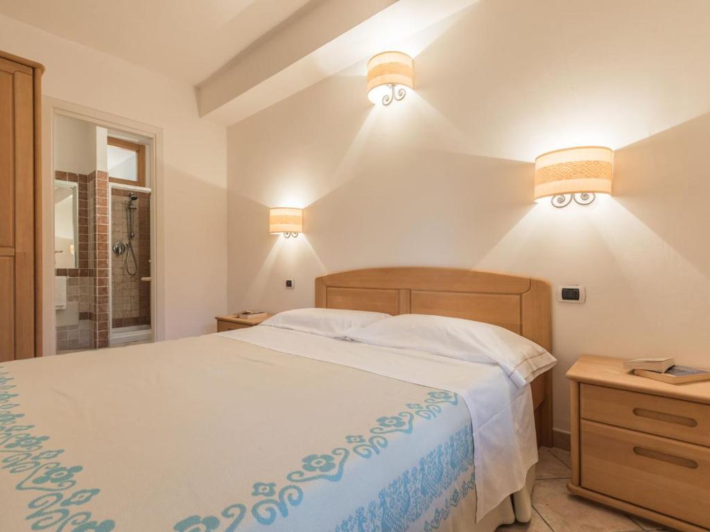 - une chambre avec un lit et deux lumières sur le mur dans l'établissement Capo Ceraso Family Resort, à Costa Corallina
