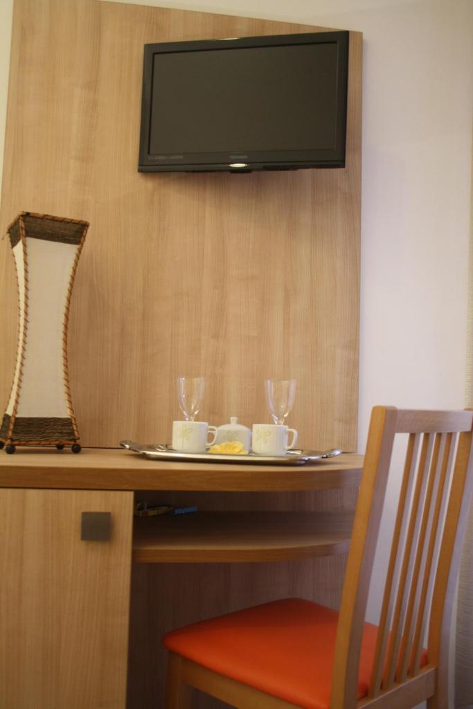 - une table avec une télévision sur un mur et des verres dans l'établissement Hotel Camelia, à Rimini