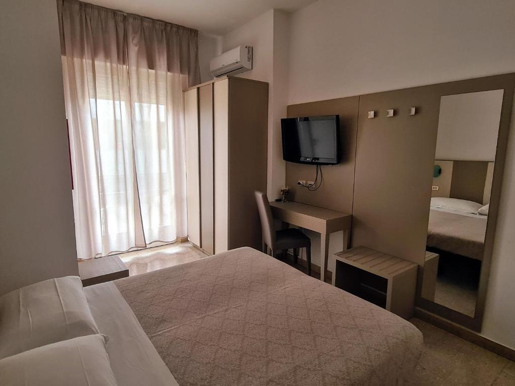 une chambre d'hôtel avec un lit, un bureau et un miroir dans l'établissement Hotel Camelia, à Rimini