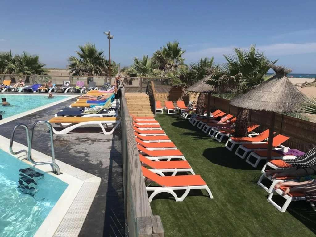 une rangée de chaises longues à côté d'une piscine dans l'établissement Camping 4 étoiles - Piscine - ccb0bab, à Portiragnes