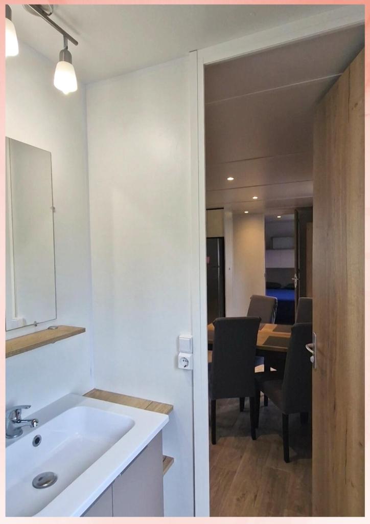 une cuisine avec un évier et une table avec des chaises dans l'établissement Les Sables du Midi, Agréable Mobilhome 6 personnes Valras Plage, à Valras-Plage