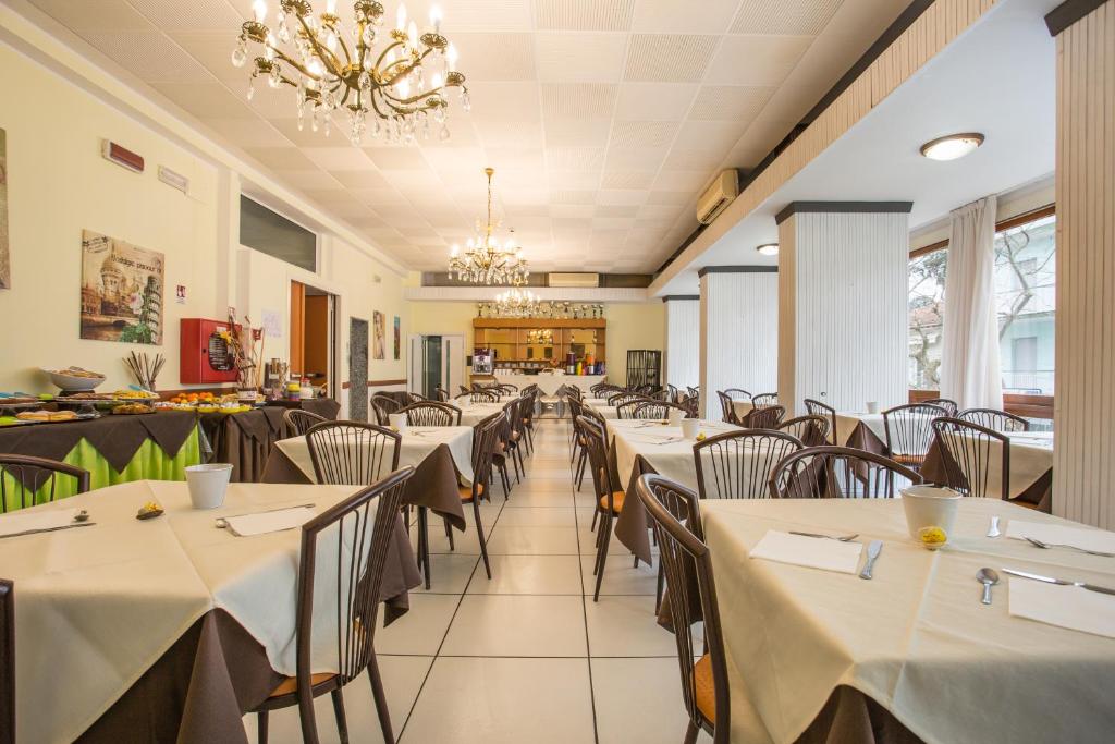 un restaurant avec des tables, des chaises et un lustre dans l'établissement Hotel Sant'Angelo, à Riccione