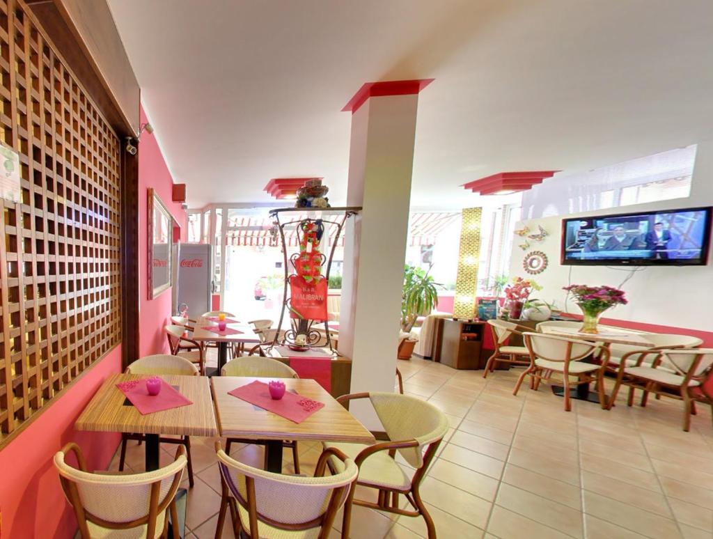 un restaurant avec des tables et des chaises et une télévision au mur dans l'établissement Hotel Malibran, à Lido di Jesolo