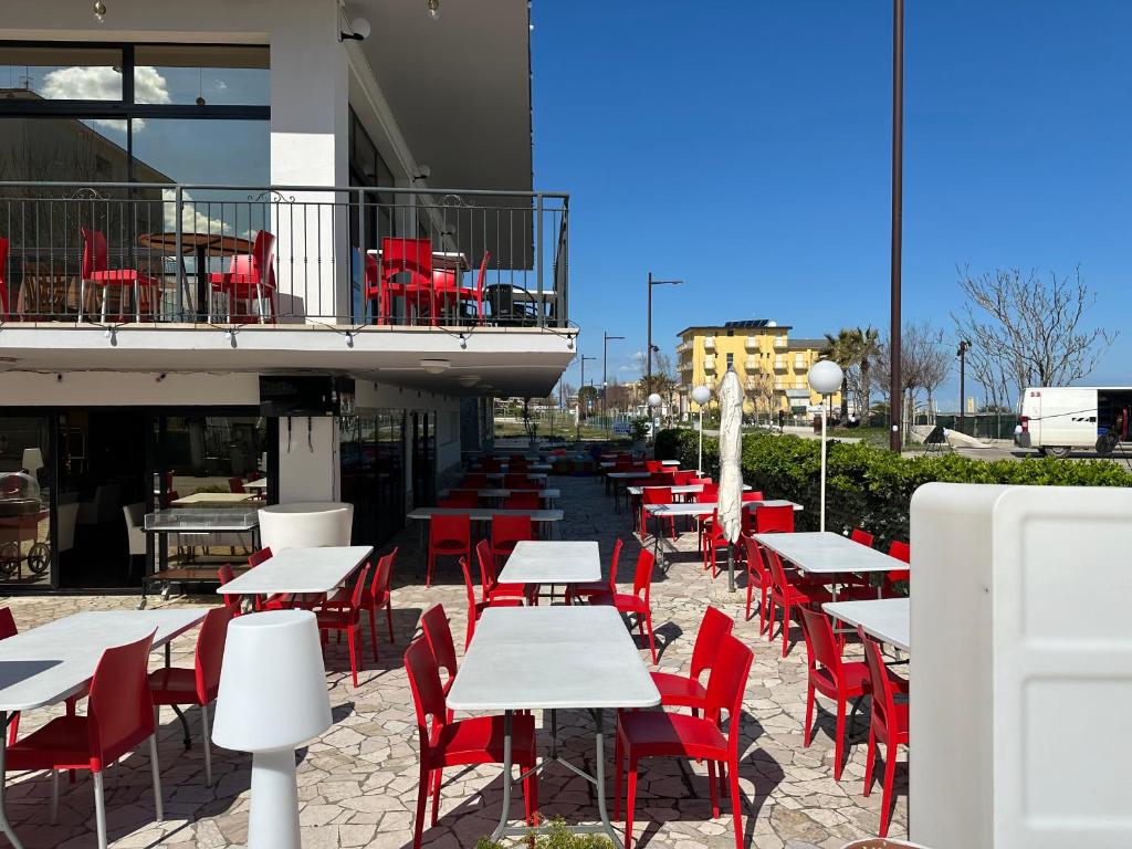 une rangée de tables et de chaises avec des chaises rouges dans l'établissement Hotel Alcazar, à Rimini