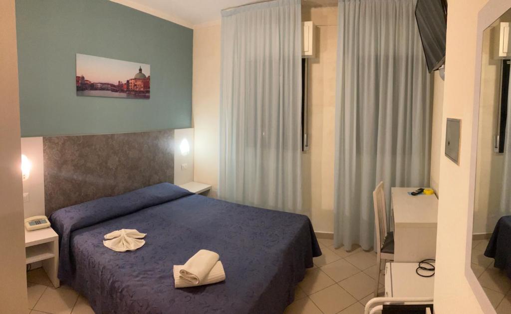 une chambre d'hôtel avec un lit bleu avec des serviettes blanches dessus dans l'établissement Hotel Senyor, à Rimini