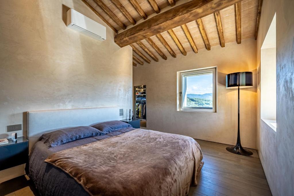 une chambre avec un grand lit et une fenêtre dans l'établissement YD exclusive design villa Agati, à Castiglion Fiorentino