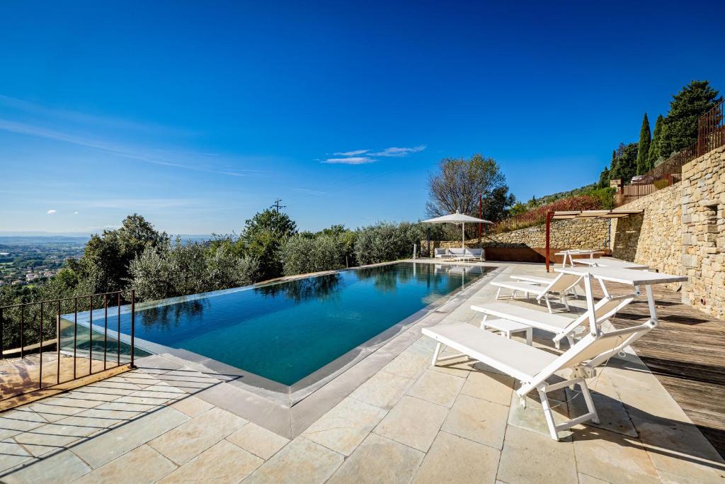 - une piscine avec 2 chaises blanches et une table dans l'établissement YD exclusive design villa Agati, à Castiglion Fiorentino