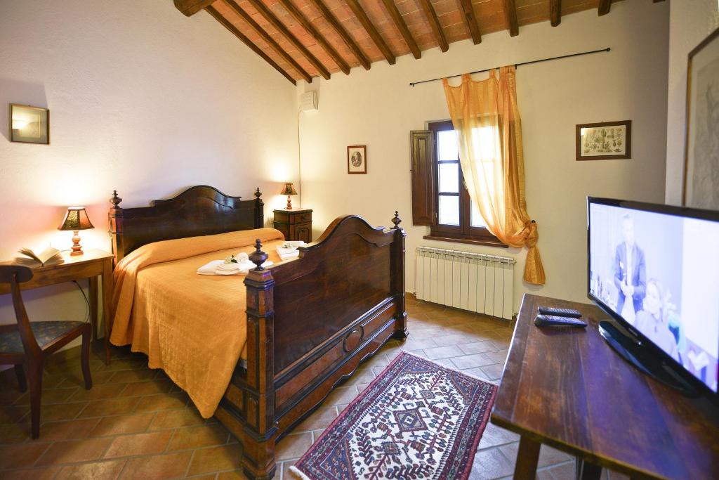 une chambre avec un lit et une télévision à écran plat dans l'établissement Podere Suvignano, à Murlo