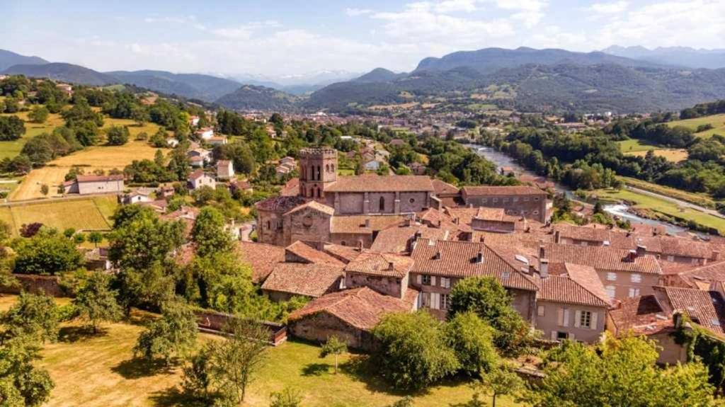 une vue aérienne sur un village avec des montagnes en arrière-plan dans l'établissement Camping 4 étoiles - Piscine - ccbadea, à La Bastide-de-Sérou