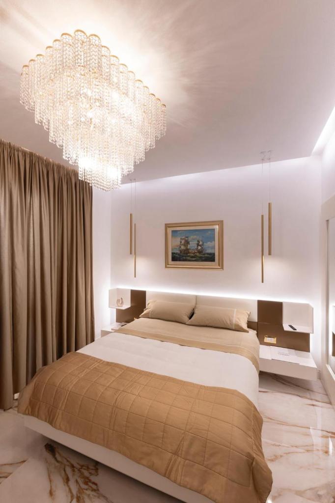 une chambre avec un grand lit et un lustre dans l'établissement Villino Peca, à Forte dei Marmi 18 autres photos