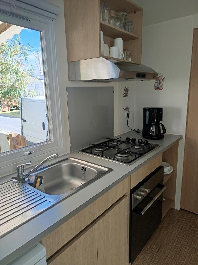 une cuisine avec un évier, une cuisinière et une fenêtre dans l'établissement SABLE DU MIDI chez gégé, à Valras-Plage