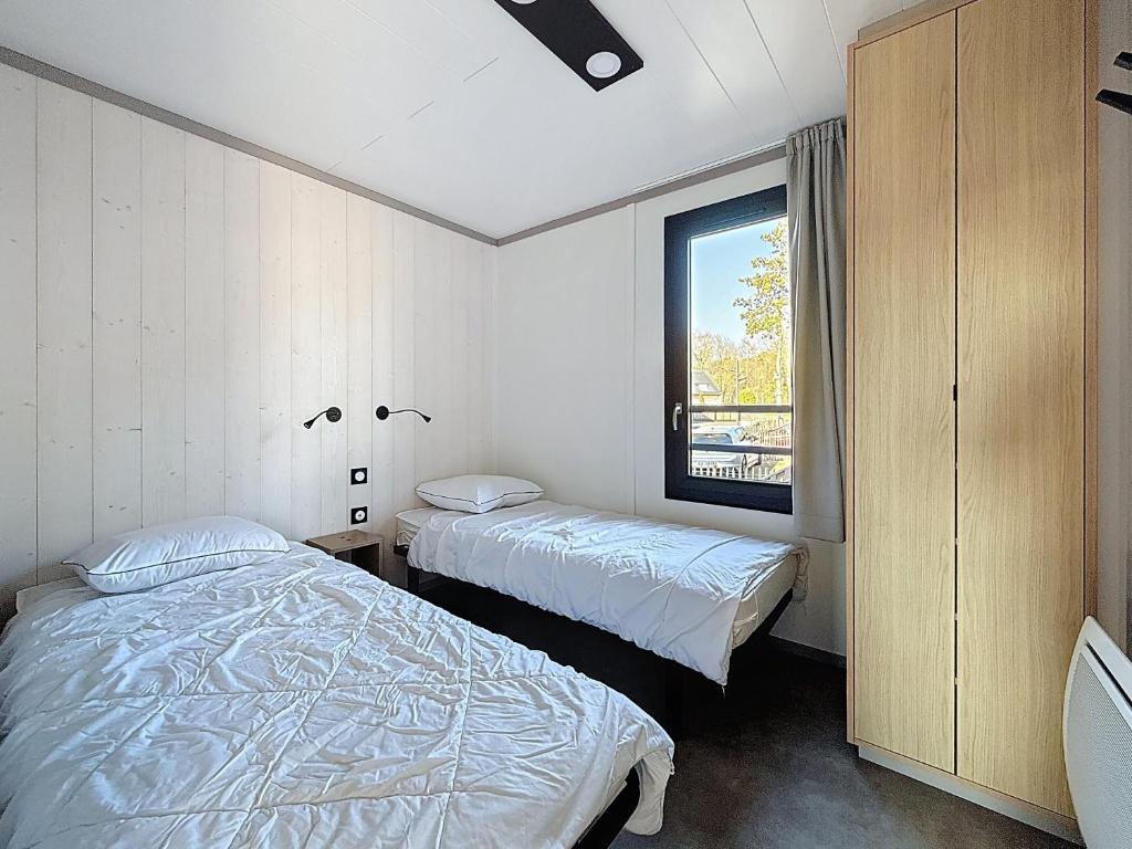 deux lits dans une chambre avec une fenêtre dans l'établissement La Criste Marine, à Jullouville
