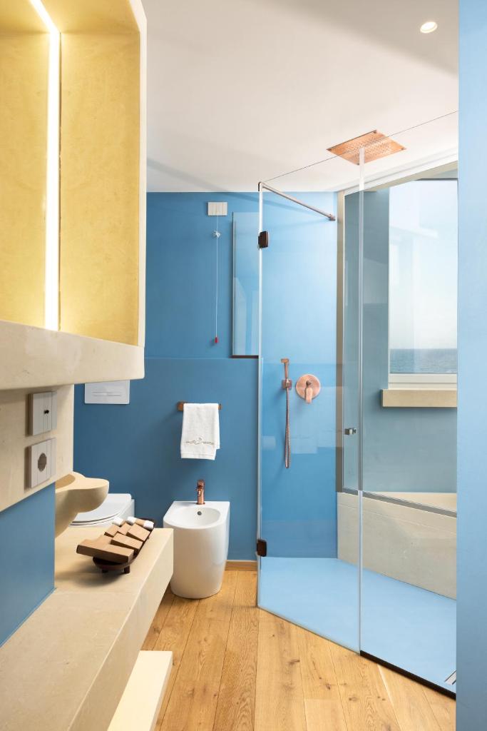 La salle de bains bleue est pourvue de toilettes et d'une douche en verre. dans l'établissement Metamare, à Cozze