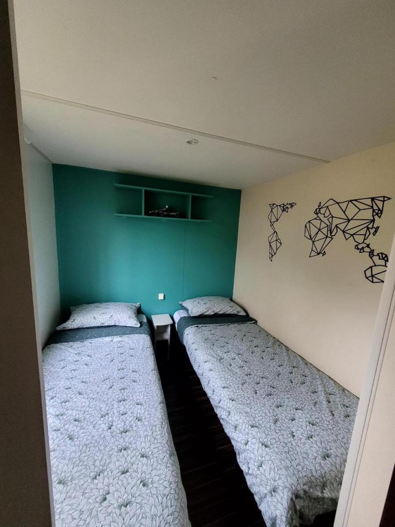 deux lits dans une chambre aux murs verts dans l'établissement Mobil home Capbreton, à Capbreton 13 autres photos