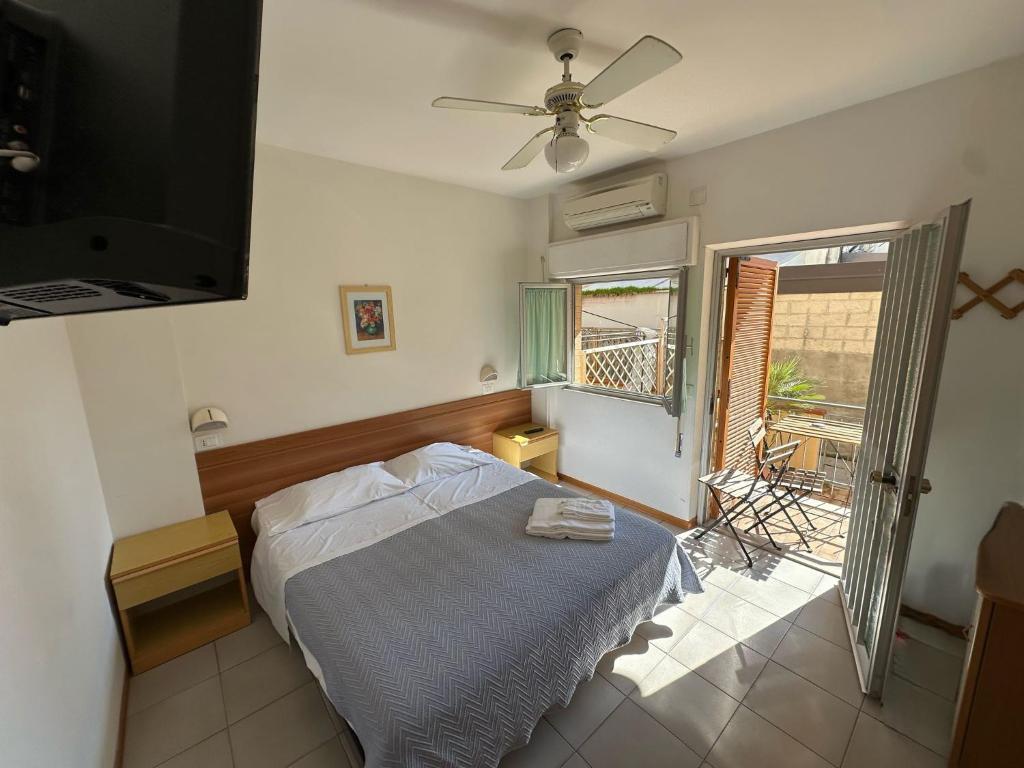 - une chambre avec un lit, un ventilateur de plafond et une fenêtre dans l'établissement Affittacamere Il Giardino, à Alba Adriatica