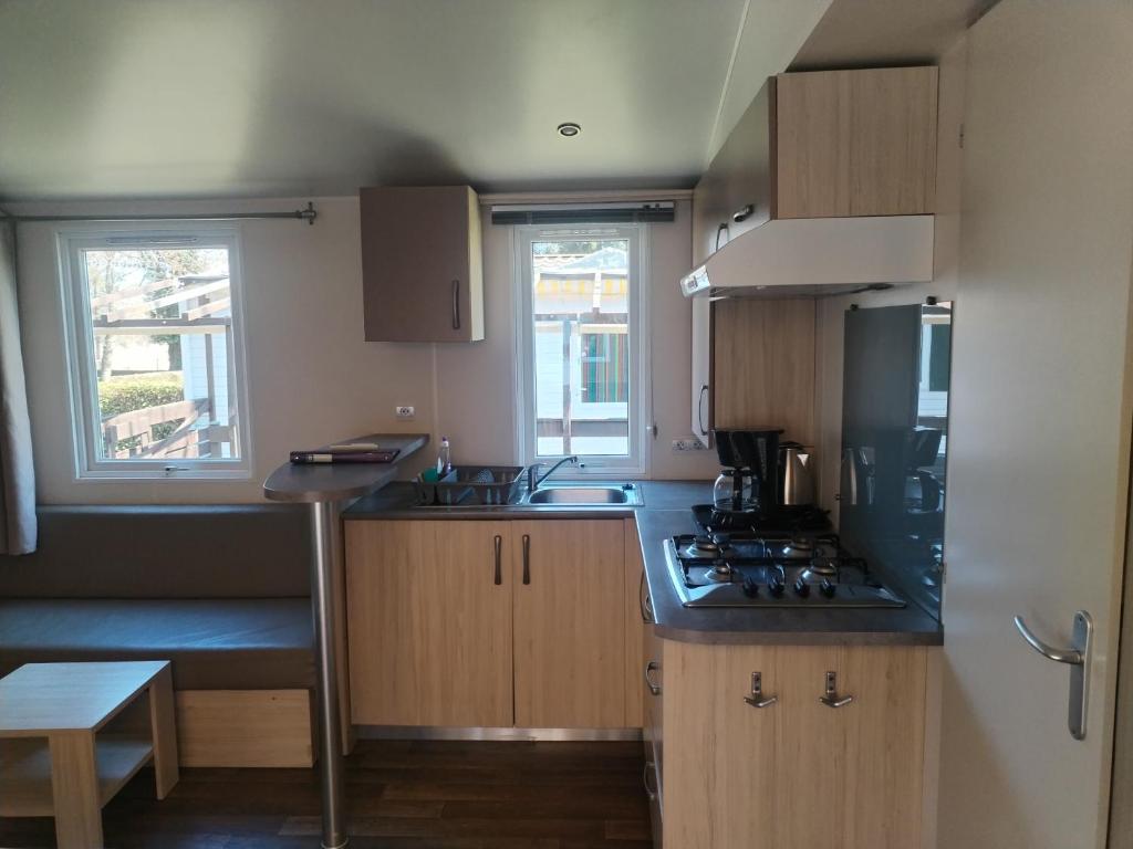 une petite cuisine avec des placards en bois et une cuisinière dans l'établissement Mobil-Home 6 personnes avec TV et clim N' B025, à Boofzheim