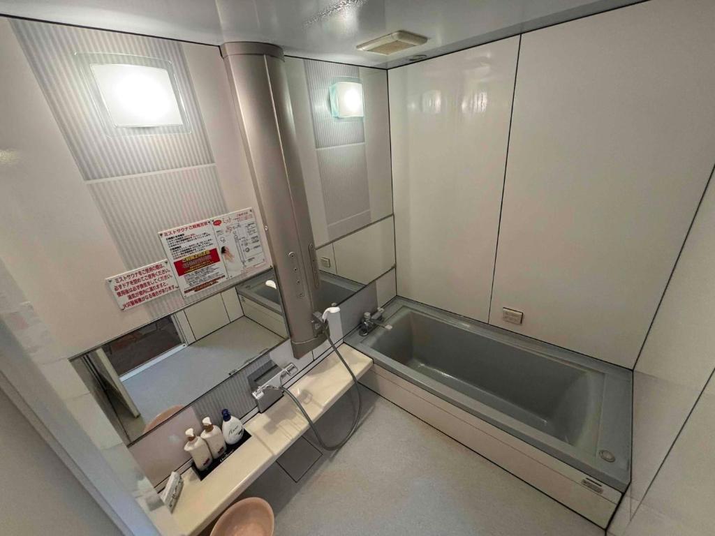 une petite salle de bain avec une baignoire et un lavabo dans l'établissement ホテル ひこうせん, à Yurihama 15 autres photos