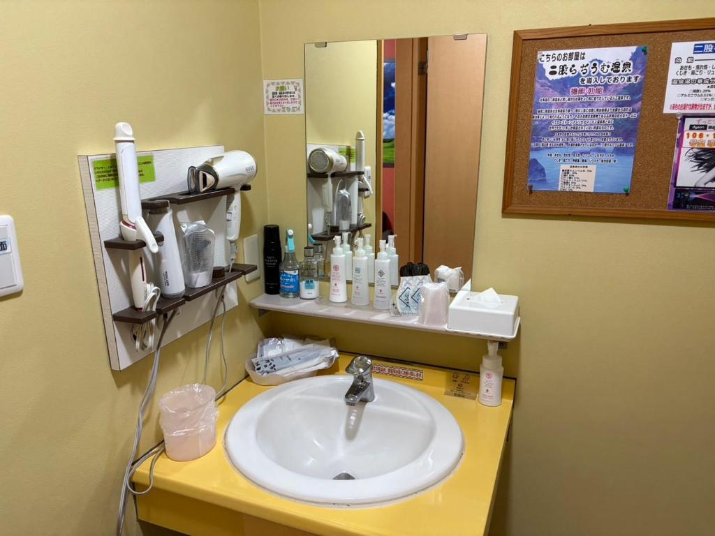 une salle de bain avec un lavabo et un miroir dans l'établissement ホテル キラリ, à Tottori
