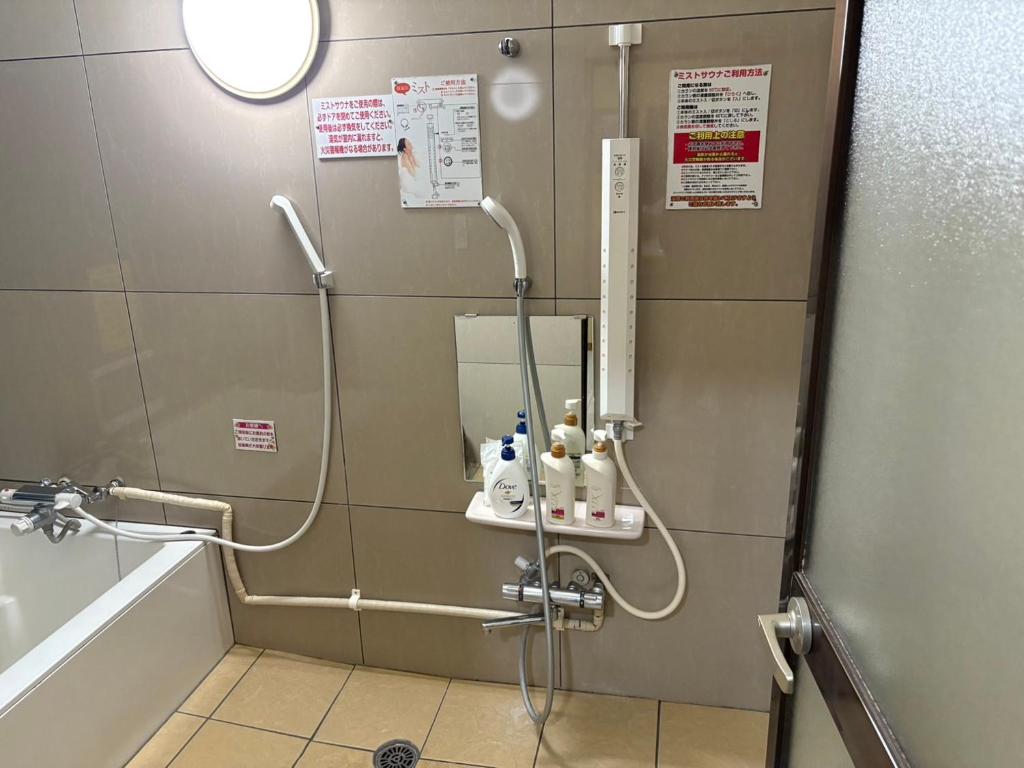 La salle de bains est pourvue d'une douche, d'une baignoire et d'un lavabo. dans l'établissement ホテル キラリ, à Tottori