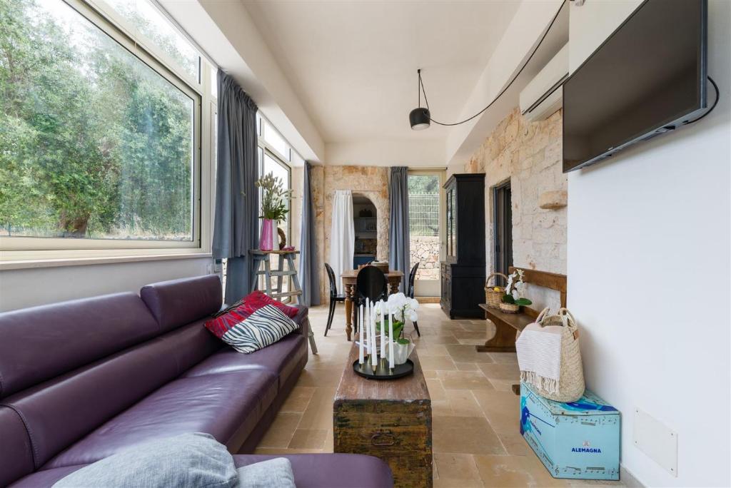 - un salon avec un canapé violet et une grande fenêtre dans l'établissement Mediterranean villa with private pool and garden, à Ostuni