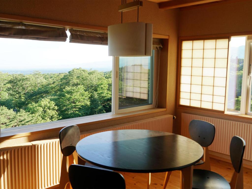 une salle à manger avec une table, des chaises et des fenêtres dans l'établissement Wakaki Ryokan - Nasu Yumoto Onsen, à Nasu