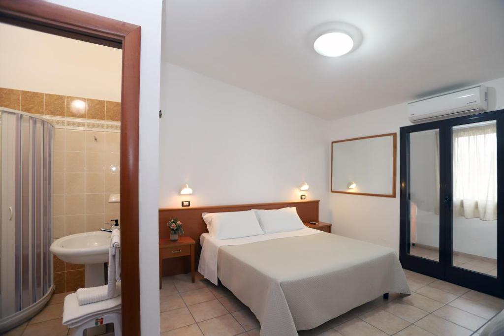 une chambre avec un lit et une salle de bain avec un lavabo dans l'établissement Residence Club Solemare, à Vieste