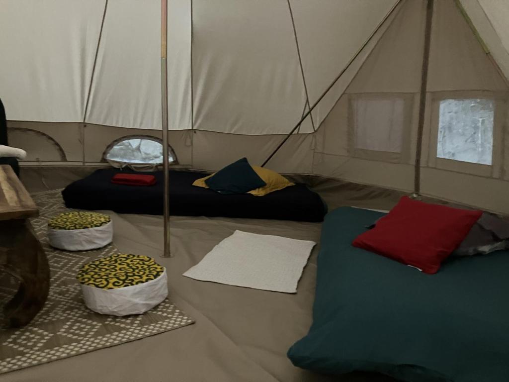 une tente avec 2 lits dans une chambre dans l'établissement Grande Tente Tipi en pleine forêt, à Burzet